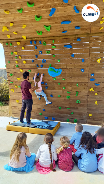 Les enfants grimpent à tour de rôle sur leur nouveau mur d'escalade avec l'équipe CLIMB IT escalade factory